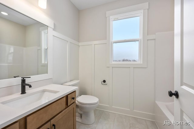 bathroom with toilet, tile patterned flooring, tub / shower combination, vanity, and a decorative wall