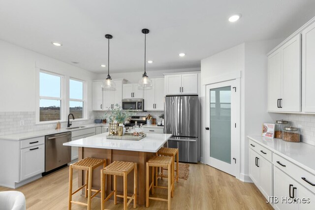 11376 Shoreline Dr Unit 115, Allendale, MI 49401 - kitchen featuring light wood finished floors, stainless steel appliances, backsplash, a breakfast bar area, and white cabinetry