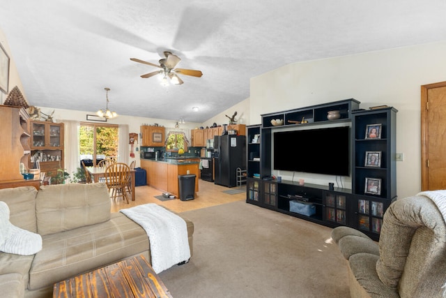 living room featuring lofted ceiling, ceiling fan with notable chandelier, light carpet, and a textured ceiling