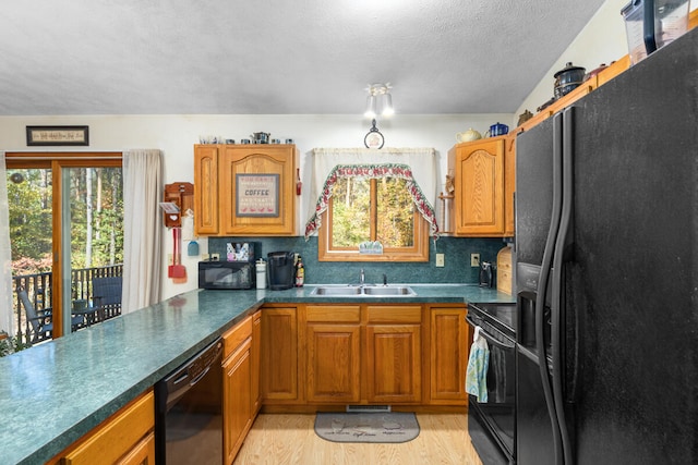 kitchen with sink, tasteful backsplash, black appliances, light hardwood / wood-style floors, and a textured ceiling