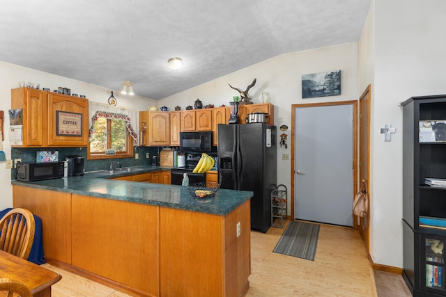 kitchen with lofted ceiling, sink, kitchen peninsula, and black appliances