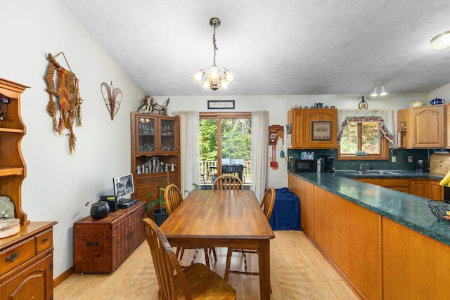 dining area with sink, a notable chandelier, and light hardwood / wood-style flooring