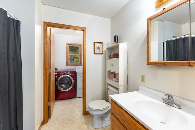 bathroom featuring vanity, washing machine and clothes dryer, and toilet