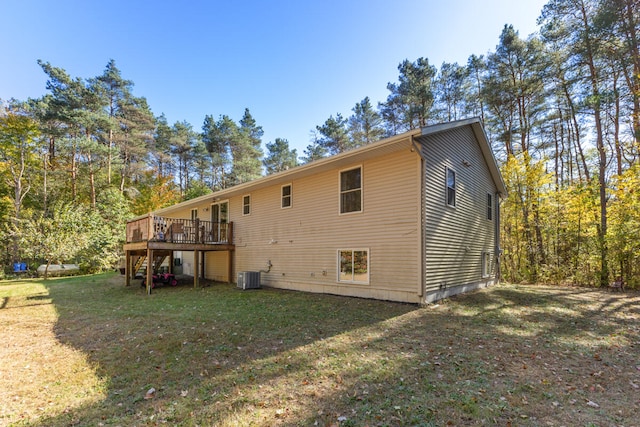 rear view of property with a wooden deck, a lawn, and cooling unit