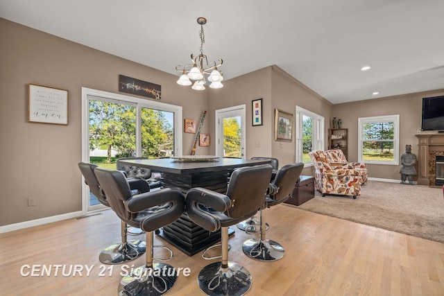 dining room featuring an inviting chandelier, light hardwood / wood-style flooring, ornamental molding, and a premium fireplace