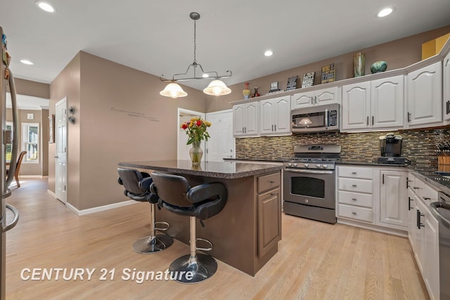 kitchen featuring white cabinetry, a center island, light wood-type flooring, and appliances with stainless steel finishes