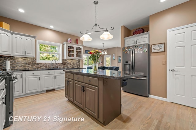 kitchen with white cabinets, stainless steel appliances, light wood-type flooring, and a kitchen island