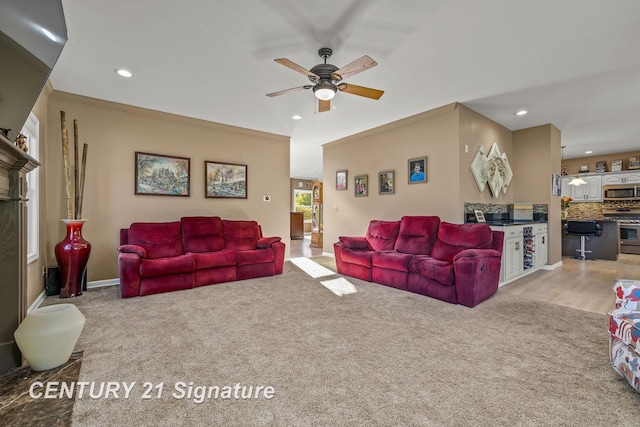 living room with ceiling fan, light colored carpet, and ornamental molding