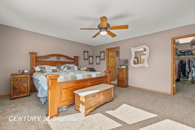 bedroom featuring a spacious closet, a closet, ceiling fan, and light carpet