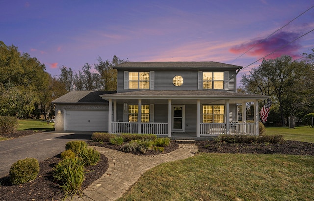 view of front of property with covered porch, a garage, and a yard