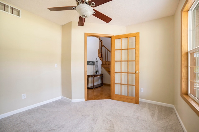 spare room featuring french doors, carpet floors, a textured ceiling, and ceiling fan