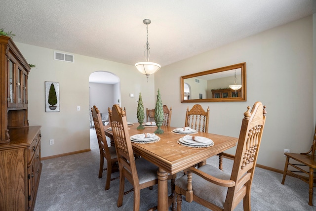 carpeted dining room with a textured ceiling