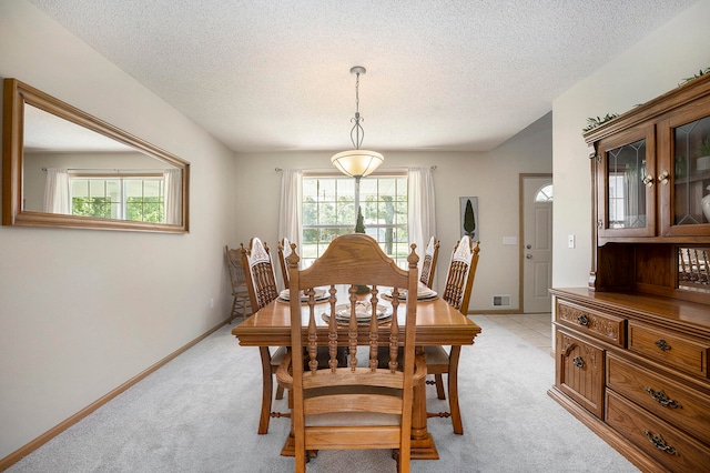 dining space with a textured ceiling and light carpet