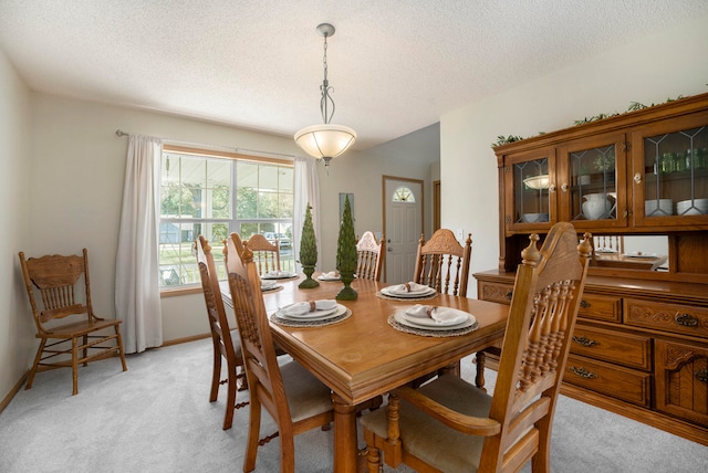 dining space with a textured ceiling and light colored carpet