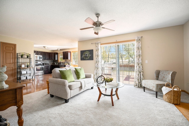 living room with ceiling fan, light hardwood / wood-style floors, and a textured ceiling