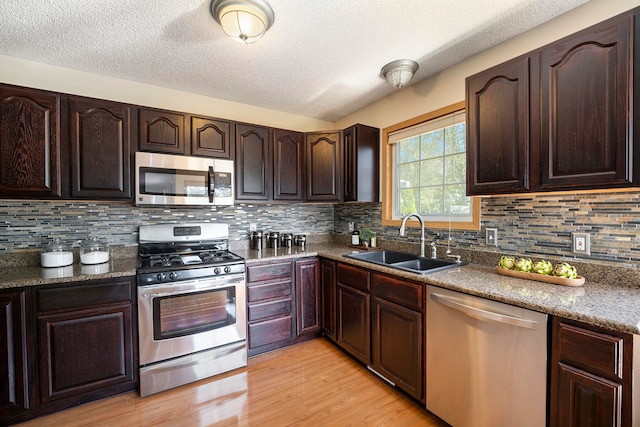 kitchen featuring backsplash, light hardwood / wood-style floors, sink, and stainless steel appliances