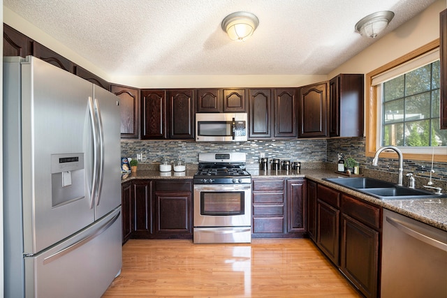 kitchen featuring a textured ceiling, sink, appliances with stainless steel finishes, and light hardwood / wood-style flooring