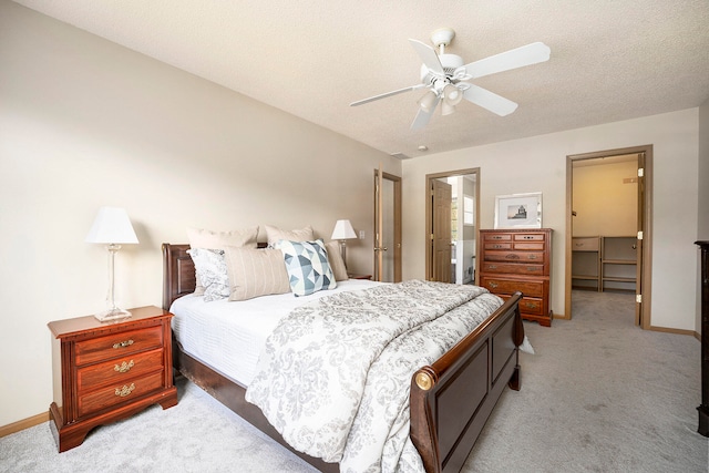 bedroom with a textured ceiling, ceiling fan, light carpet, and ensuite bath