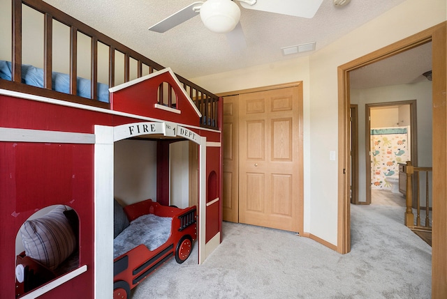 carpeted bedroom featuring ceiling fan, a textured ceiling, and a closet