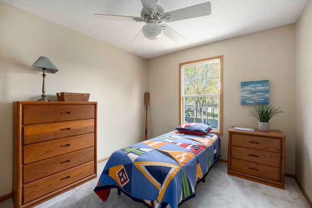 bedroom with ceiling fan, light carpet, and a textured ceiling