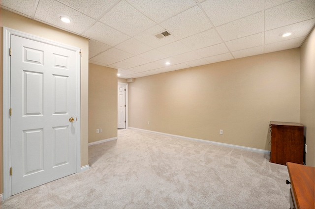 basement with a paneled ceiling and light colored carpet