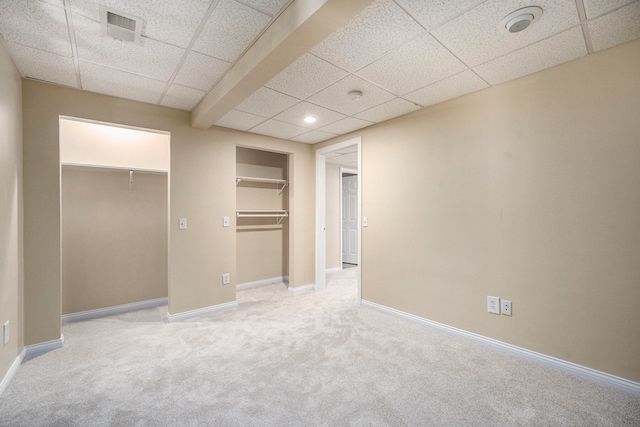 unfurnished bedroom featuring a paneled ceiling, a closet, and light colored carpet