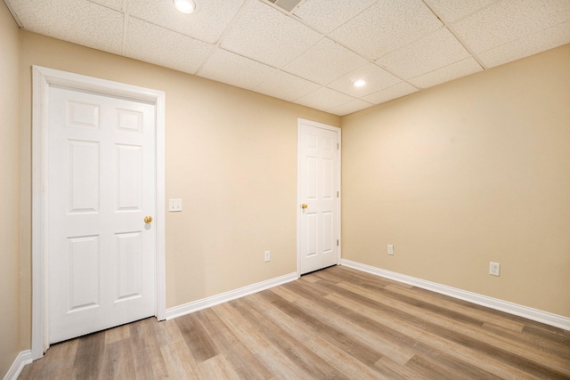 spare room with a paneled ceiling and hardwood / wood-style flooring