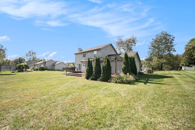 view of yard with a trampoline, a pergola, and a wooden deck