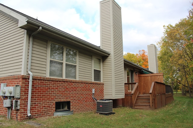 view of side of property with a lawn, central AC, and a deck