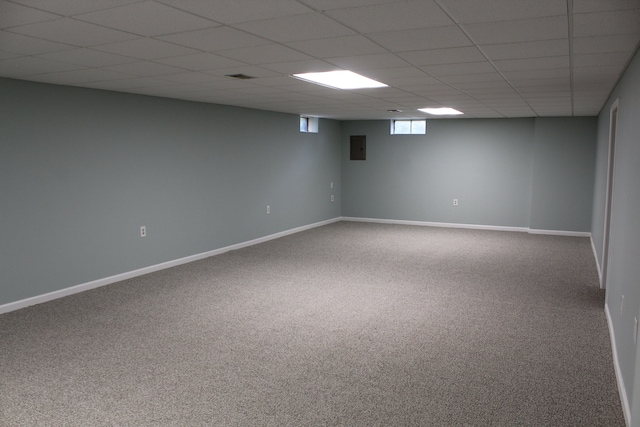 basement with a paneled ceiling, electric panel, and carpet floors