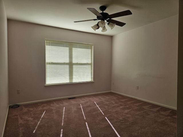 empty room with dark colored carpet and ceiling fan