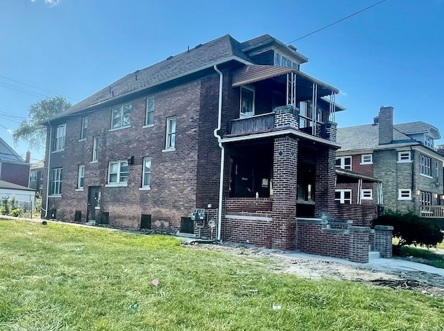 view of side of home featuring a balcony and a lawn