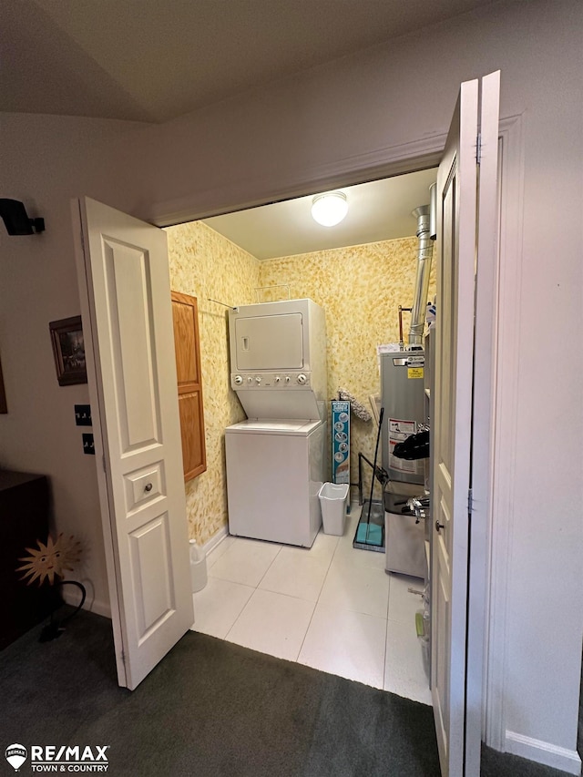 washroom with light tile patterned floors, stacked washing maching and dryer, and gas water heater