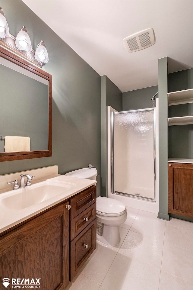 bathroom with tile patterned floors, a shower with door, vanity, and toilet