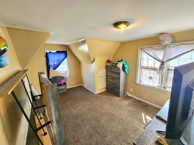 additional living space with dark colored carpet, vaulted ceiling, and a healthy amount of sunlight