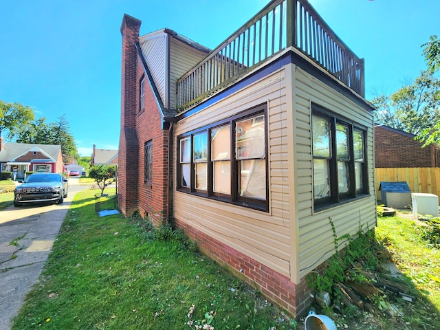 view of side of property with a balcony and a yard