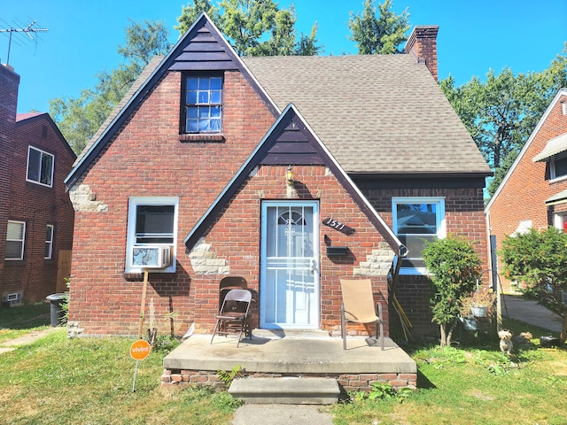 tudor house with a front yard and cooling unit