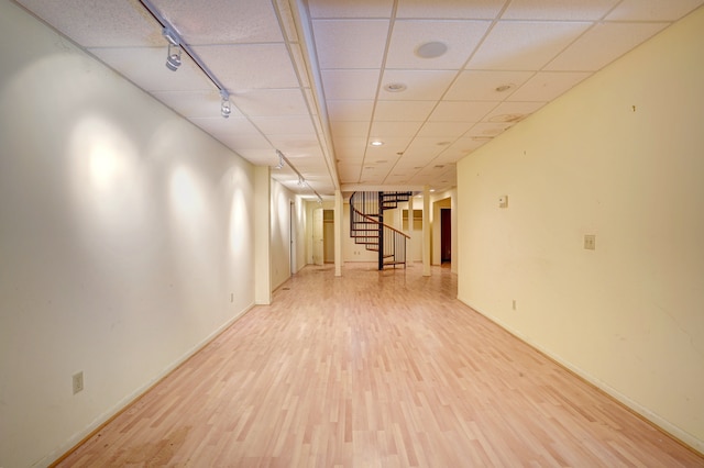 basement featuring a paneled ceiling and wood-type flooring