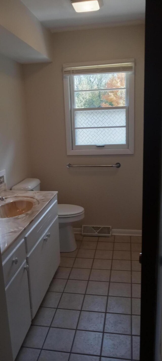 bathroom with tile patterned floors, vanity, a healthy amount of sunlight, and toilet