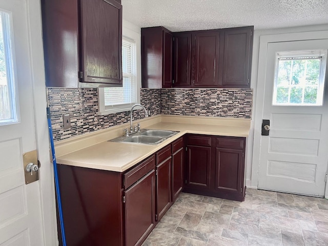 kitchen with a textured ceiling, backsplash, and sink