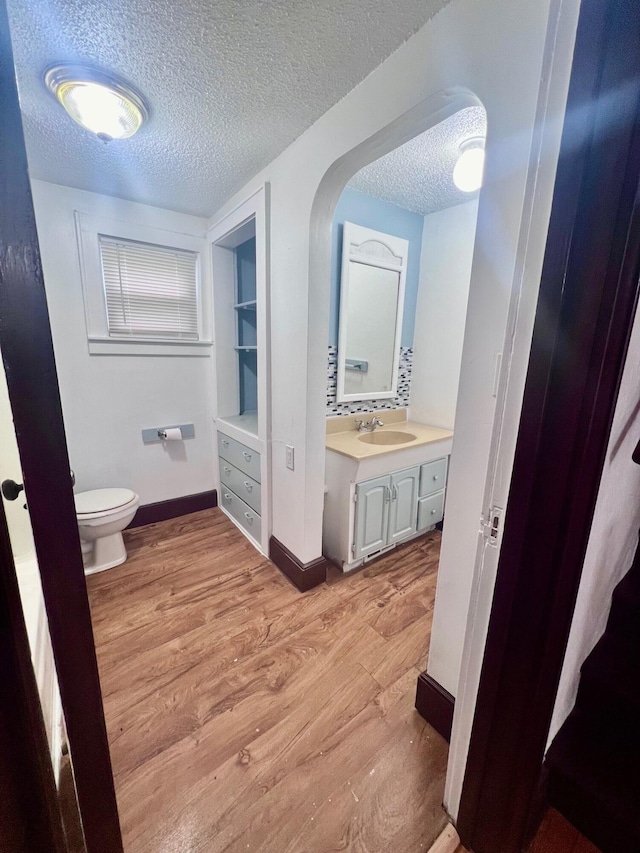 bathroom featuring vanity, hardwood / wood-style floors, a textured ceiling, and toilet