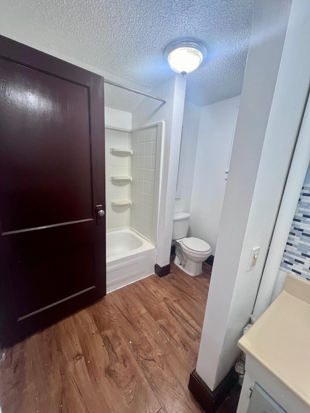 bathroom featuring toilet, bathtub / shower combination, a textured ceiling, and hardwood / wood-style flooring