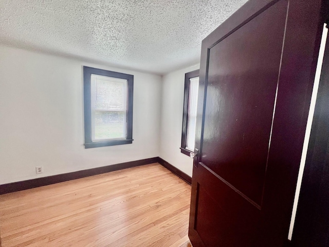 spare room featuring a textured ceiling and light hardwood / wood-style flooring