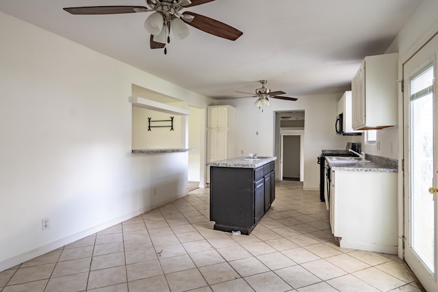 kitchen with white cabinetry, light tile patterned floors, ceiling fan, and stainless steel range oven