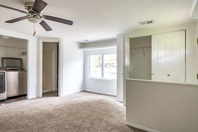 unfurnished living room featuring washer and clothes dryer, ceiling fan, and light carpet