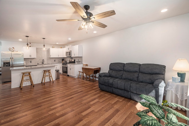 living room with ceiling fan, dark wood-type flooring, and sink