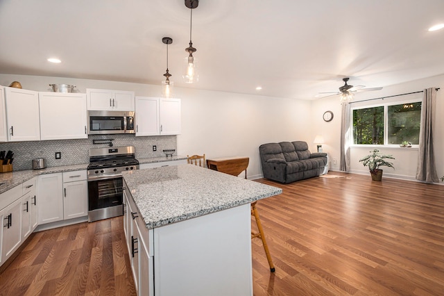 kitchen with white cabinets, appliances with stainless steel finishes, dark hardwood / wood-style flooring, and hanging light fixtures