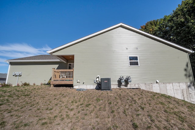 view of property exterior with a deck, central AC unit, and a lawn