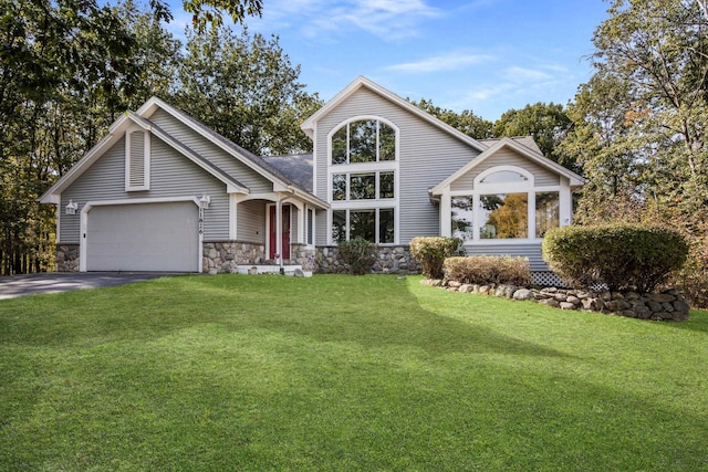 11826 Ridge View Dr, Rapid City, MI 49676 - traditional-style home featuring asphalt driveway, stone siding, an attached garage, and a front yard