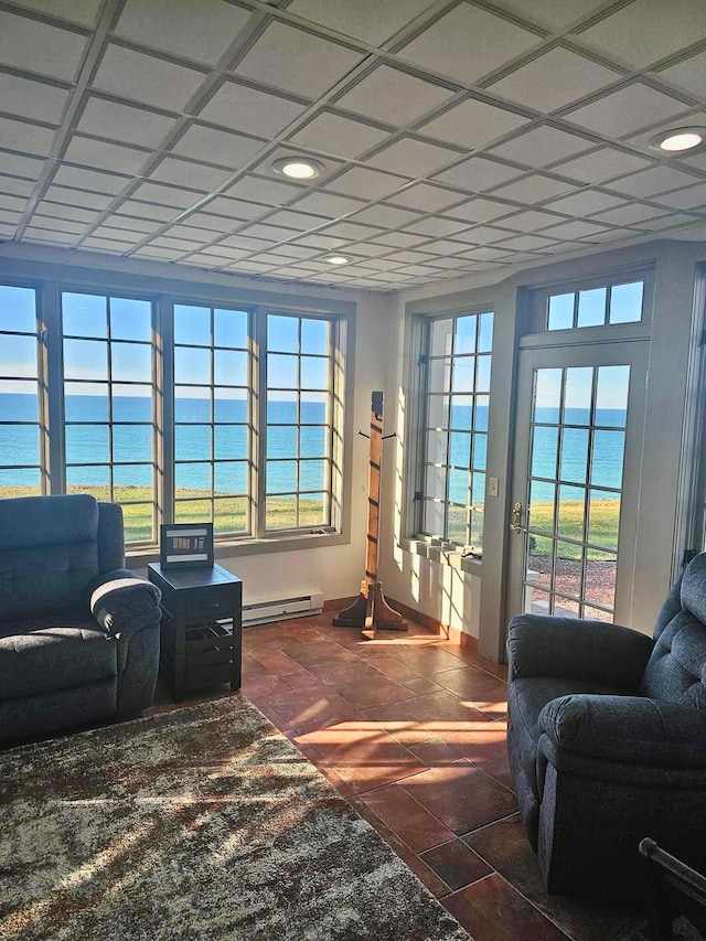 living room with dark tile patterned floors, plenty of natural light, a water view, and a baseboard heating unit